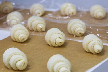 Çiğ hamurdan oluşan kruvasanlar fırına gönderilmeden önce kağıt üzerinde yatar. El yapımı pasta pişirme süreci