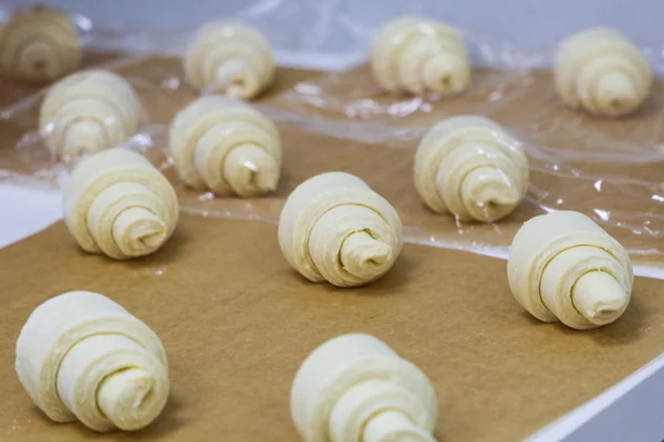 Croissants Utworzone Surowego Ciasta Leżą Papierze Pieczenia Przed Wysłaniem Piekarnika — Zdjęcie stockowe