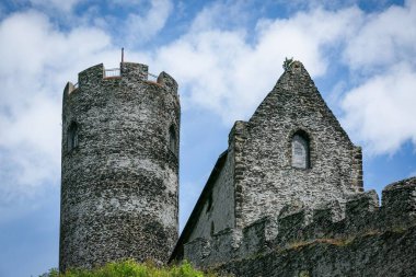 Bezdez, Çek Cumhuriyeti - 19 Temmuz 2020: Bir kule ve ev manzarası, kayalık bir tepenin üzerinde duran gri taşlardan yapılmış ortaçağ şatosunun parçaları. Mavi gökyüzü ve beyaz bulutlarla güneşli bir gün..