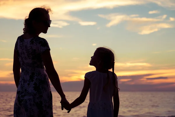 Moeder en dochter spelen op het strand op de zonsondergang keer. — Stockfoto