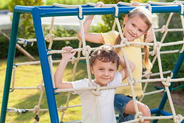 Frère et sœur heureux jouant sur le terrain de jeu — Photo