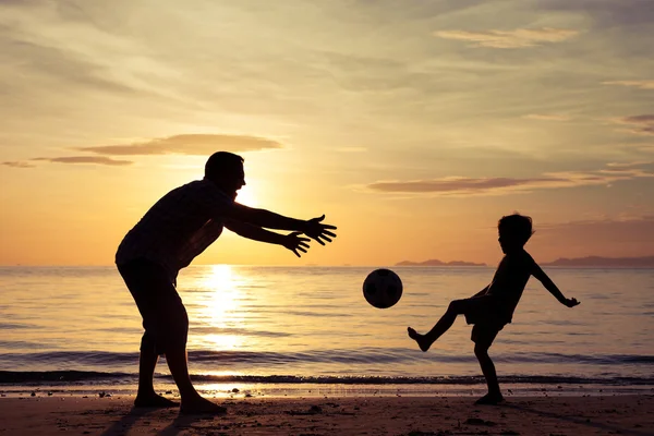 Pai e filho brincando na praia na hora do pôr do sol . — Fotografia de Stock