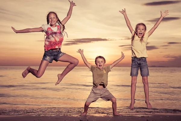 De gelukkige kinderen spelen op het strand op de zonsondergang keer. — Stockfoto