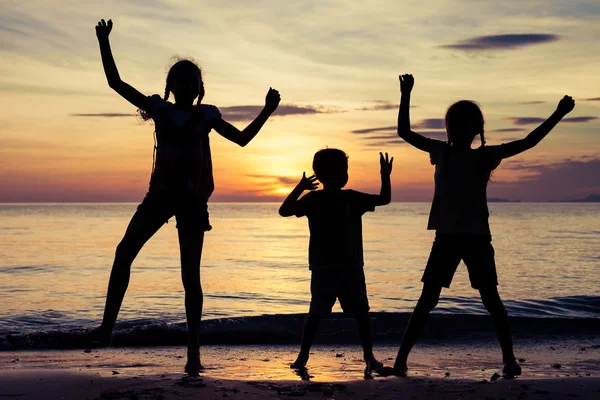 Glada barn som leker på stranden vid solnedgången tid. — Stockfoto
