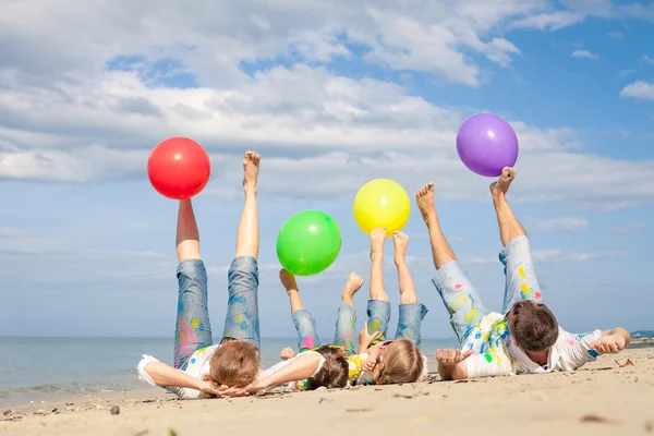 Família feliz brincando na praia na hora do dia . — Fotografia de Stock