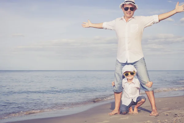 Far och son som spelar på stranden på dagarna. — Stockfoto