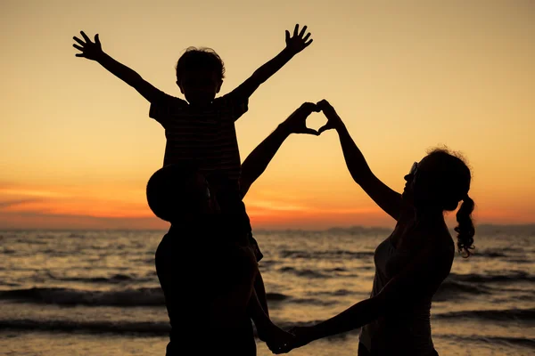 Silhouet van gelukkige familie die spelen op het strand bij de sunse — Stockfoto