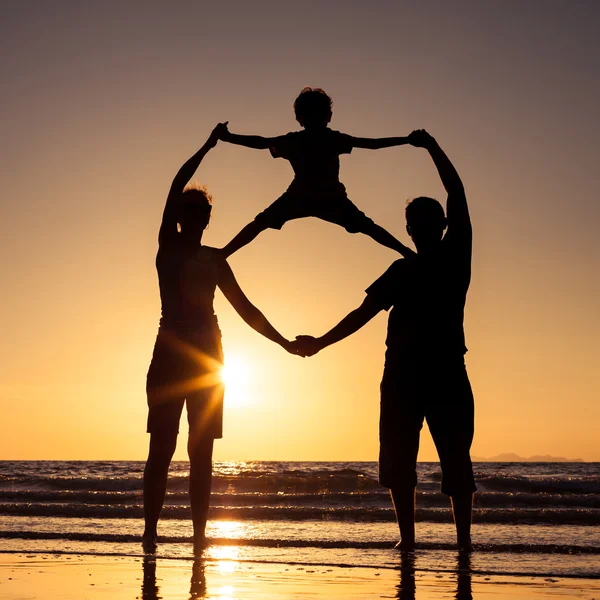 Silhueta de família feliz que joga na praia ao sol — Fotografia de Stock