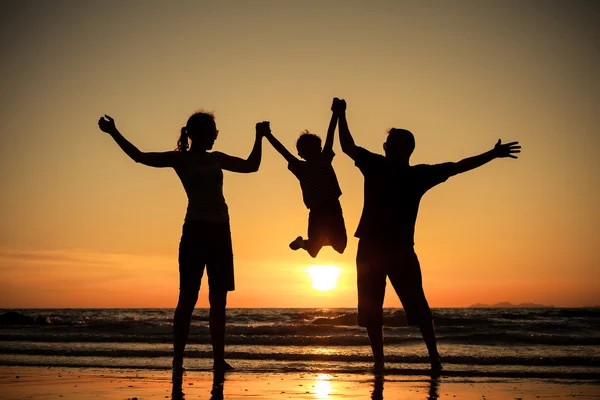 Silueta de familia feliz que juega en la playa al atardecer — Foto de Stock