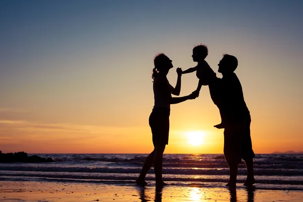 Silhueta de família feliz que joga na praia ao sol — Fotografia de Stock