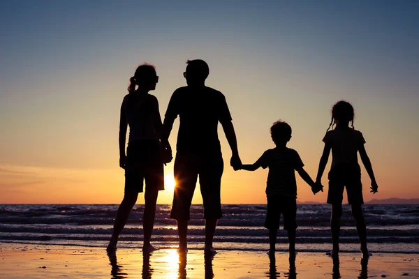 Silueta de familia feliz que juega en la playa al atardecer — Foto de Stock