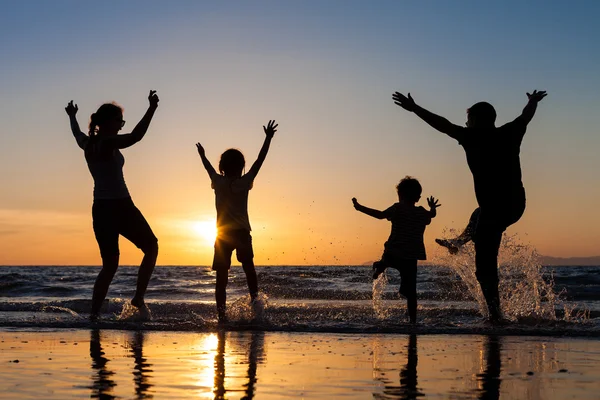 Silhouet van gelukkige familie die spelen op het strand bij de sunse — Stockfoto