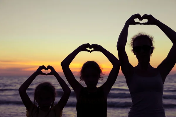 Moeder en dochters spelen op het strand bij de zonsondergang keer. — Stockfoto