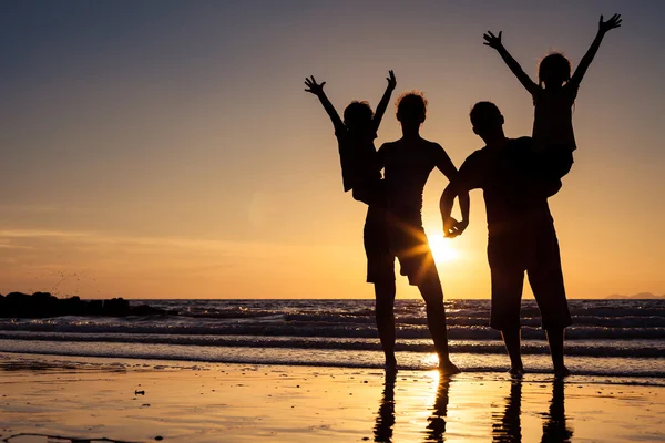 Silhouette einer glücklichen Familie, die am Strand an der Sonne steht — Stockfoto