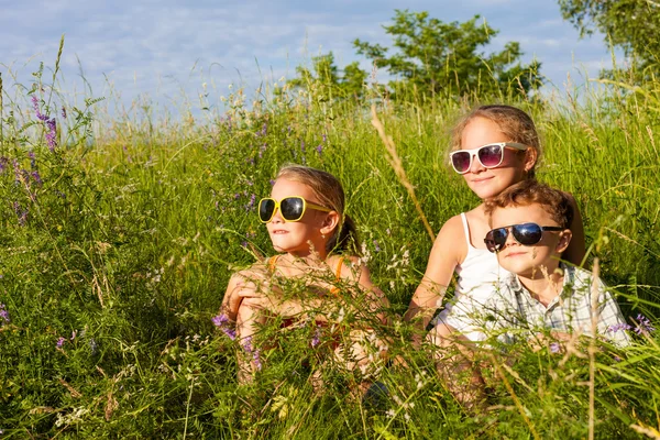 Drei glückliche Kinder, die tagsüber neben dem Baum spielen. — Stockfoto