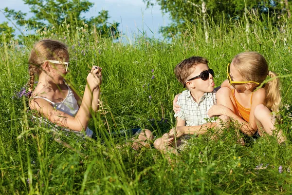 Tres niños felices jugando cerca del árbol durante el día . — Foto de Stock