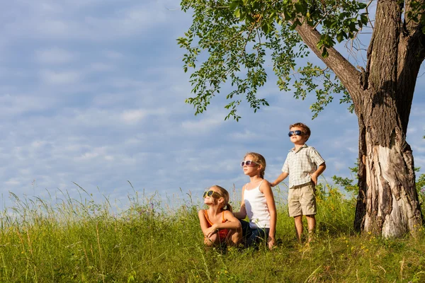 Trois enfants heureux jouant près de l'arbre le jour . — Photo