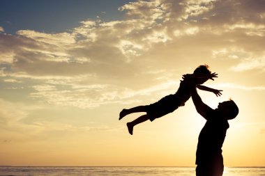 Baba ve oğul sahilde günbatımı anda oynamak.