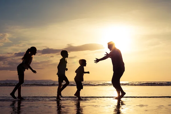 Padre e hijos jugando en la playa al atardecer . —  Fotos de Stock