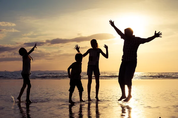 Padre e figli che giocano in spiaggia al tramonto . — Foto Stock