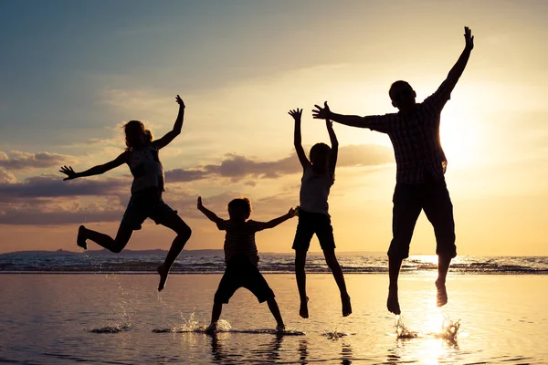 Pai e crianças brincando na praia na hora do pôr do sol . — Fotografia de Stock