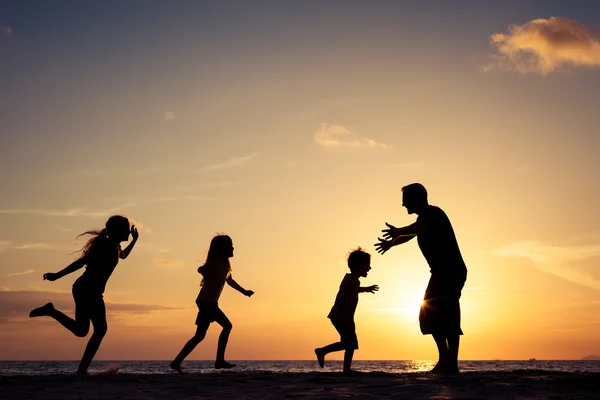 Ojciec i dzieci bawiące się na plaży w trakcie zachód. — Zdjęcie stockowe