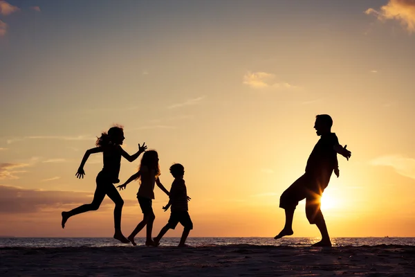 Vater und Kinder spielen am Strand bei Sonnenuntergang. — Stockfoto