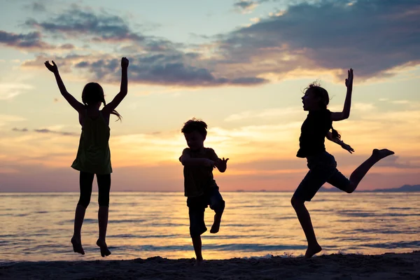 Enfants heureux jouant sur la plage au coucher du soleil . — Photo