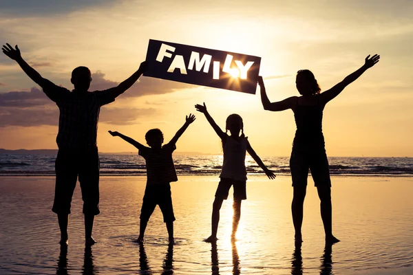 Família feliz em pé na praia na hora do pôr do sol . — Fotografia de Stock