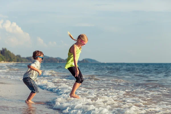 Niños felices jugando en la playa durante el día . — Foto de Stock