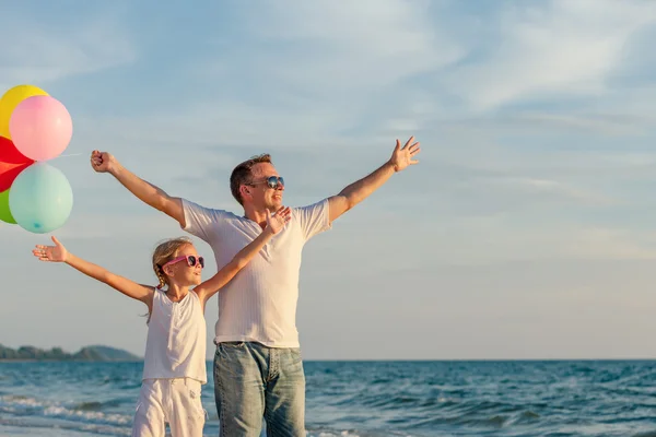 Vader en dochter met ballonnen spelen op het strand aan de da — Stockfoto