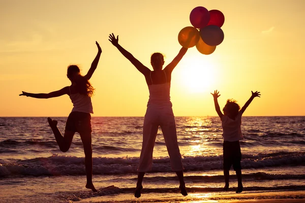 Mor och barn som leker med ballonger på stranden vid su — Stockfoto