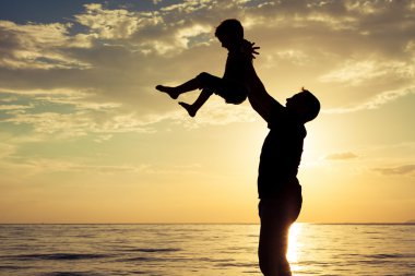 Baba ve oğul sahilde günbatımı anda oynamak.