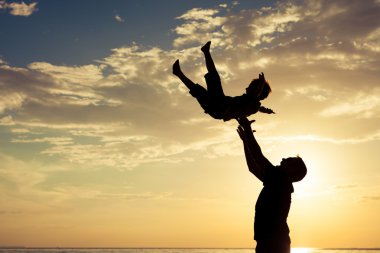 Baba ve oğul sahilde günbatımı anda oynamak.