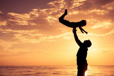 Baba ve oğul sahilde günbatımı anda oynamak.