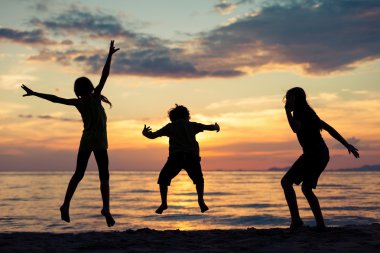 Mutlu çocuk sahilde günbatımı anda oynamak.