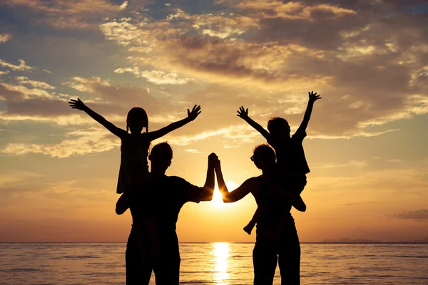 Silhouette of happy family who playing on the beach at the sunse Stock Image