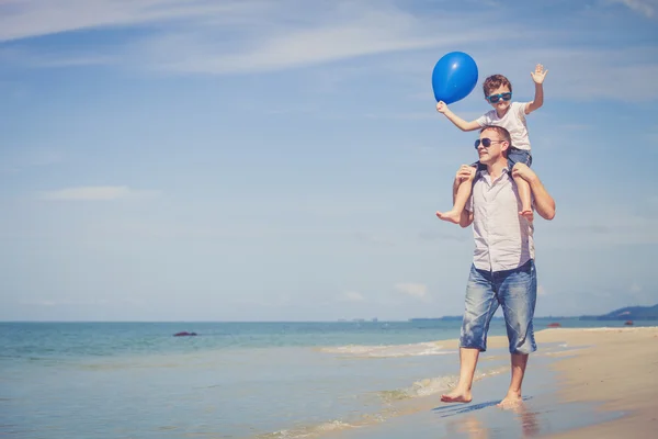 Far och son som spelar på stranden på dagarna. — Stockfoto