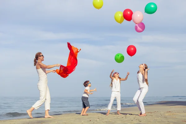 Moeder en kinderen spelen op het strand op het moment van de dag. — Stockfoto