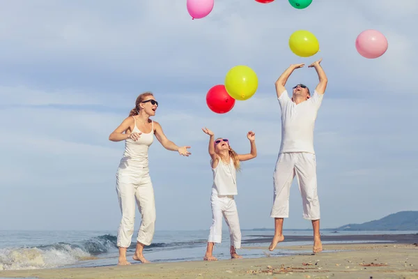 Lycklig familj med ballonger spelar på stranden på dagarna. — Stockfoto
