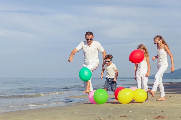 Otce a děti si hrají na pláži v denní době. — Stock fotografie