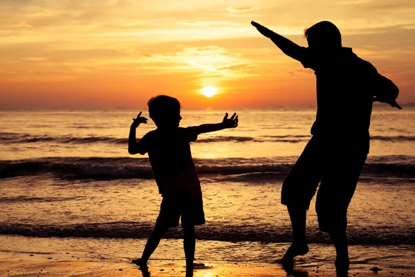 Father and son  playing  on the beach at the sunset time. — Zdjęcie stockowe
