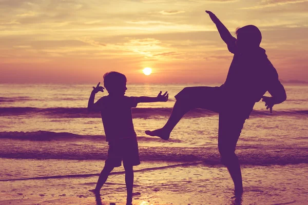 Père et fils jouant sur la plage au coucher du soleil . — Photo