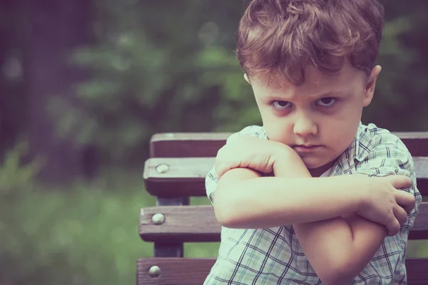 Porträt eines traurigen kleinen Jungen auf einer Bank — Stockfoto