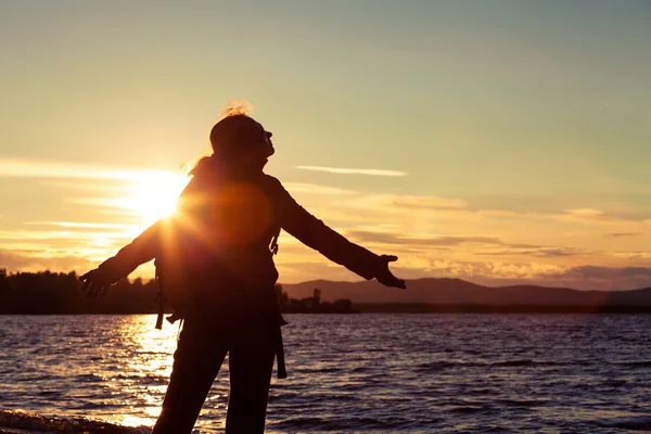 Silhouette donna libera in piedi vicino al lago tra le montagne — Foto Stock