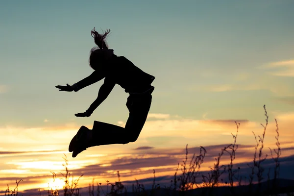 Happy girl jumping  on the coast of lake  of at the sunset time. — Stock Photo, Image