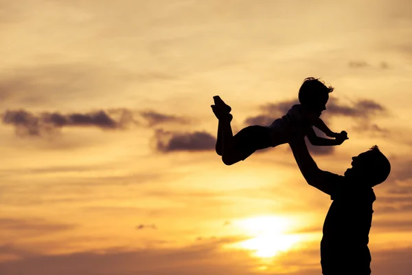 Vader en zoon spelen op het strand op de zonsondergang keer. — Stockfoto