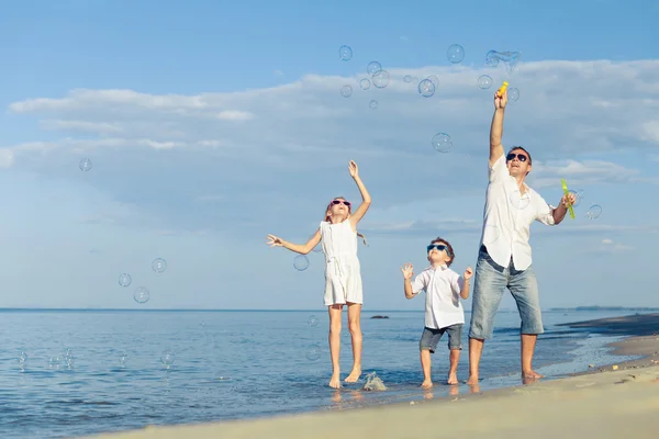 Far och barn som leker på stranden på dagarna. — Stockfoto