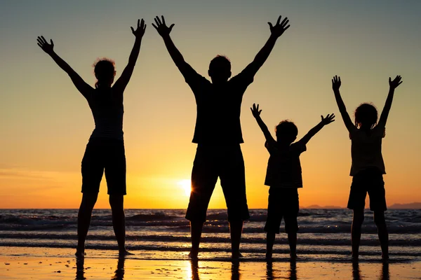 Silhueta de família feliz que de pé na praia nos sóis — Fotografia de Stock