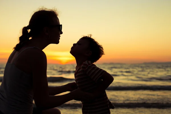 母亲和儿子在日落的时候在海滩上玩. — 图库照片